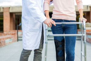 Male Physician helping assist a female use a walker.